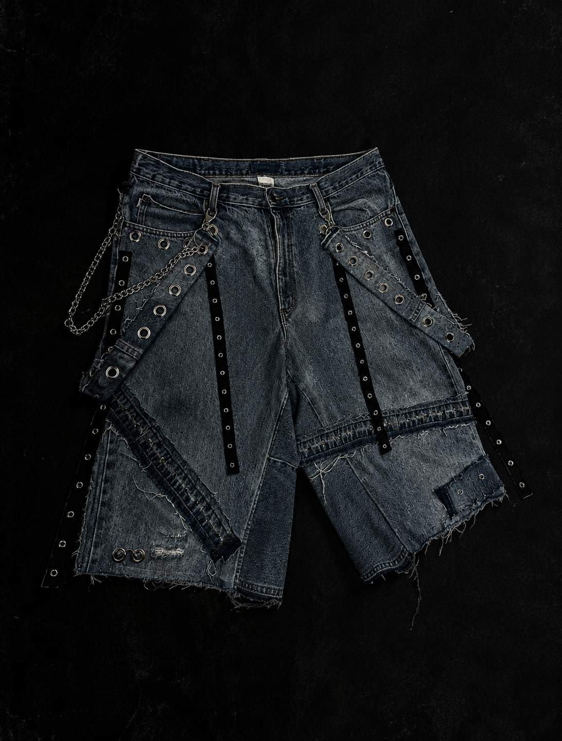 Bermuda de denim Vandal con diseño deconstruido, ojillos, cadenas y accesorios metálicos urania club