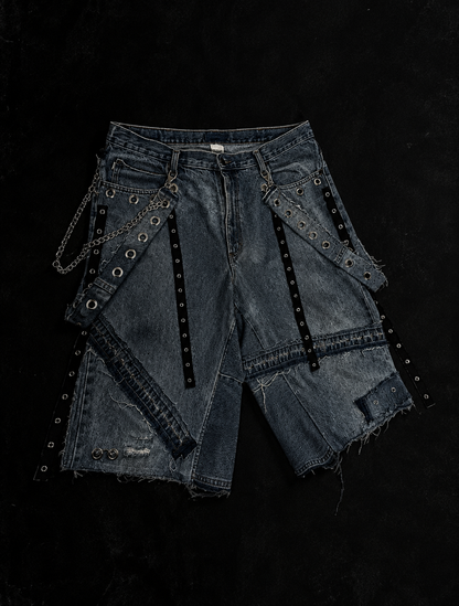 Bermuda de denim Vandal con diseño deconstruido, ojillos, cadenas y accesorios metálicos urania club