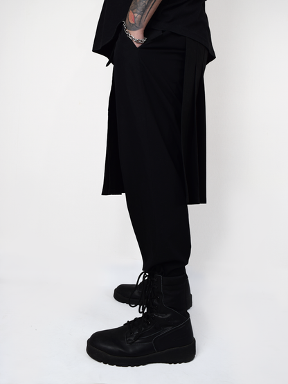 Sobrecapa tipo kilt negro industrial utilizada sobre pantalón estilo streetwear alternativo